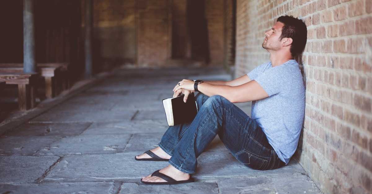 Ein junger Man sitzt verzweifelt an einer Mauer, in der Hand eine ausgedruckte Vereinssatzung
