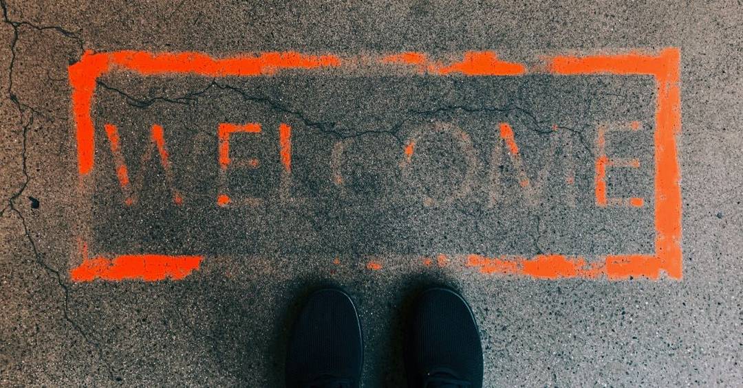 Nahaufnahme einer Straße, darauf mit Sprühfarbe der Schriftzug "Welcome"