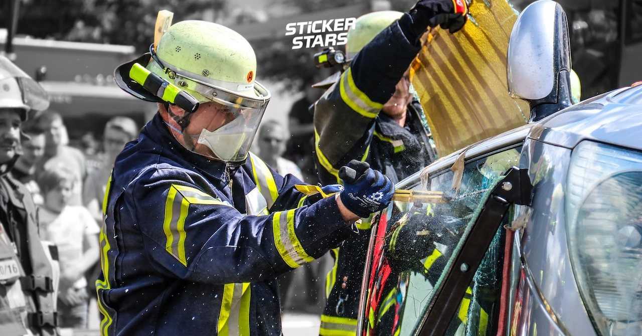 Zwei Feuerwehrleute zeigen auf einem Feuerwehrfest, wie man Menschen aus einem Autowrack befreit
